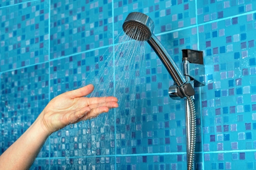 A woman checking to see if her shower is losing water pressure. 