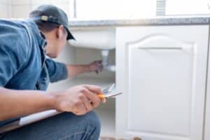 plumber inspects under the kitchen sink