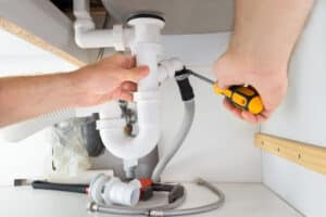 plumber repairing pipe under the sink