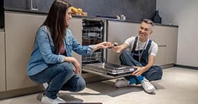 man and woman fix a dishwasher