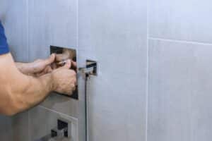 Hands of person work on installing contemporary shower fixture in stylish bathroom detailed process of fixture installation.