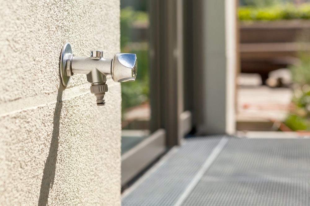 Tap Water on outside wall. Outdoor garden Faucet on yard background.