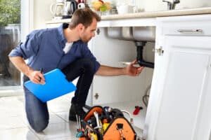 Plumber inspecting pipes under sink