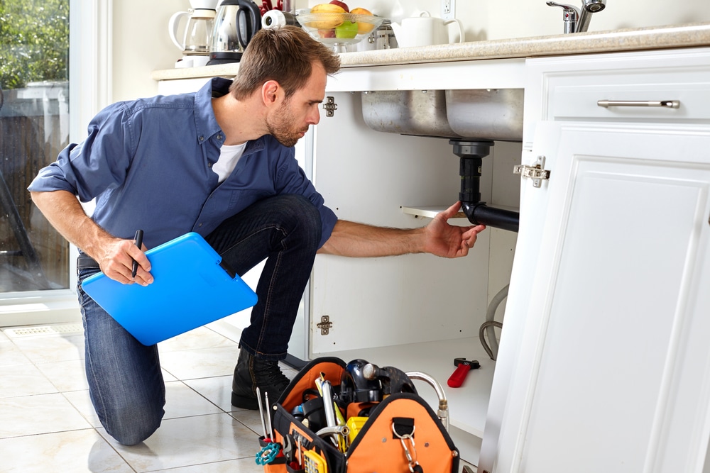 Plumber inspecting pipes under sink