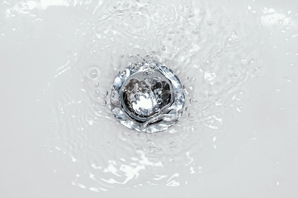 Water swirling down into a drain in bathroom sink. Concept of hygiene, cleaning, sanitation and plumbing. Drainage system and wash basin maintenance.