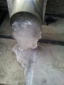 Frozen water flowing from drain or sanitary pipe in winter season: A photo for icy background.