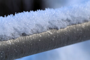 A closeup of a frozen silver colored metal pipe. Photographed during a cold winter day in Finland. You can see the beautiful texture made by the frost crystals and snow flakes. Lovely texture!